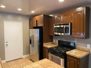 a kitchen with wooden cabinets and stainless steel appliances at Modern Stay - Private Room in Long Beach