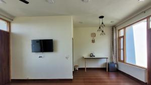 a living room with a tv on a white wall at Salig Hotel in Dharamshala
