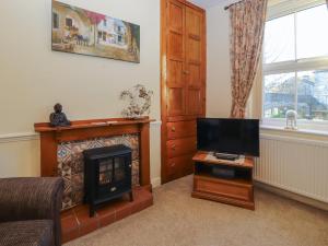 a living room with a fireplace and a television at Waterfall Cottage in Carnforth