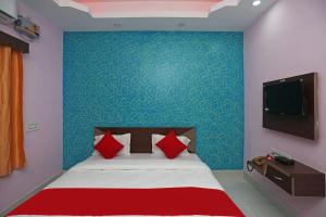 Schlafzimmer mit einem Bett mit roten Kissen und einem TV in der Unterkunft Goroomgo Savashi Puri in Puri