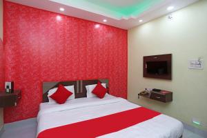 sypialnia z czerwoną ścianą z łóżkiem i telewizorem w obiekcie Goroomgo Savashi Puri w mieście Puri