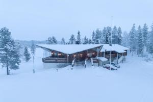 una cabaña de madera en la nieve con nieve en Hotel Kuusamon Portti en Kuusamo