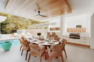 a dining room with a table and chairs and a pool at Belle Escapes Villa by the C in Palm Cove