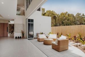 a patio with white furniture and a fence at Belle Escapes Villa by the C in Palm Cove