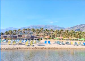 a beach with chairs and umbrellas and palm trees at La Palma Apartments,a beachfront paradise! in Georgioupolis