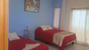 2 camas en una habitación con paredes azules en Hostal Cabañas Don Jorge, en Puerto Baquerizo Moreno