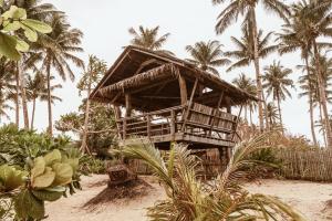 a bamboo house on the beach with palm trees at ALON CLOUD9, beach front in Catangnan