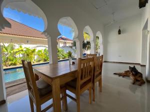 a dog laying on the floor next to a dining room table at UKAYA VILLA in Paje