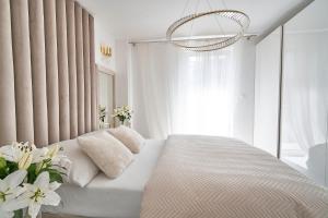 Un dormitorio blanco con una cama con flores. en SZAFIROWE APARTAMENTY 1 kryty basen i sauna RESORT KLIFOWA, en Rewal