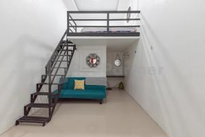 Cette chambre blanche dispose d'un lit en mezzanine et d'un canapé vert. dans l'établissement JM Guest House Lamaran RedPartner, à Karawang