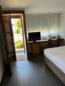 a bedroom with a bed and a desk with a computer at Hôtel Campanile Cahors in Cahors