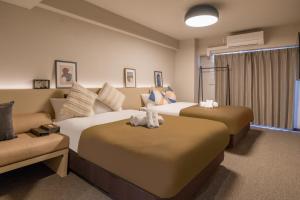 a hotel room with two beds and a couch at Apartment Hotel 11 Namba Minami III in Osaka
