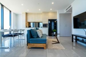 een woonkamer met een blauwe bank en een keuken bij In the heart of Surfers Paradise oceanview cozy 1B Apt 34F in Gold Coast