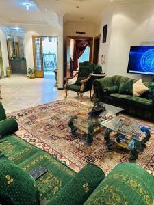 دور بغرفتين نوم في المحمدية شمال الرياض في الرياض: غرفة معيشة مع أرائك خضراء وتلفزيون