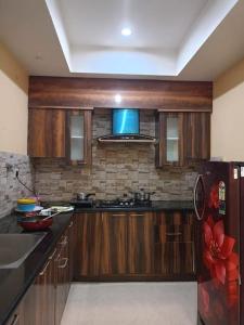uma cozinha com armários de madeira e um frigorífico preto em Babylon - Luxurious yet Homely Facility em Guwahati