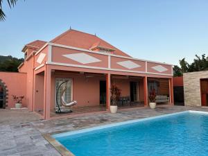 une maison avec une piscine en face de celle-ci dans l'établissement Suite by Villa Serena - Manapany les bains, à Saint-Joseph