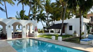 a villa with a swimming pool and palm trees at Sawa Sawa Beach House in Msambweni