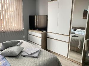 1 dormitorio con 1 cama, TV y espejo en NJ Luxury rooms and suites, en Varna