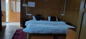 HOTEL TAWANG HOLIDAY Tawang في تاوانج: غرفة نوم بسرير كبير مع شراشف بيضاء