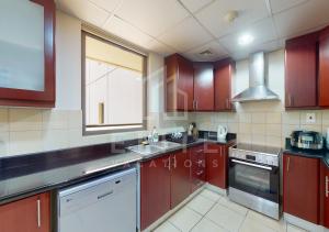 eine Küche mit roten Schränken, einem Waschbecken und einem Fenster in der Unterkunft Beautiful & Cozy 1BR on JBR Beach! in Dubai