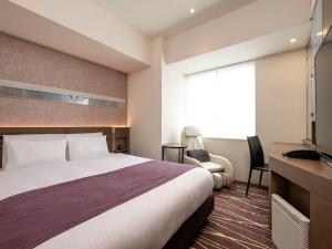 um quarto de hotel com uma cama grande e uma secretária em remm plus Ginza em Tóquio