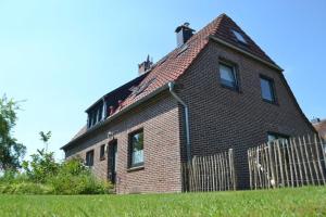 a brick house with a fence in front of it at Apart-Smutje in Stick +20 photos