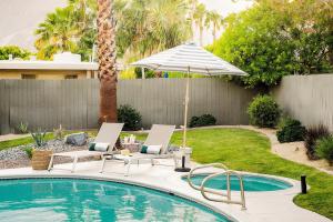 a swimming pool with two chairs and an umbrella at El Mirador by AvantStay Canyon Views Large Pool Outdoor Grill Games Permit4253 in Palm Springs