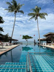 a swimming pool with palm trees and the ocean at Sea Shell Beach Resort in Ko Lanta