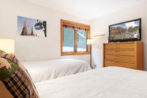 a bedroom with two beds and a tv on a dresser at Riverside Condos D01 by AvantStay Condo Close To Downtown Town Park Ski Lift 8 in Telluride