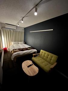 a bedroom with a bed and a green chair at Rento Park Shiba 501 in Tokyo