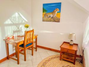 a dining room with a desk and a cheetah painting on the wall at Heart of Africa Lodge in Arusha