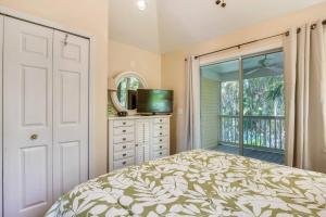 a bedroom with a bed and a tv and a window at Cottage by the Pool by AvantStay w Balcony BBQ Shared Pool Month Long Stays Only in Stock Island