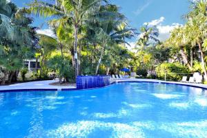 a large blue swimming pool with palm trees at Cottage by the Pool by AvantStay w Balcony BBQ Shared Pool Month Long Stays Only in Stock Island
