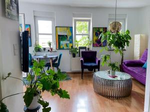 Beautiful bright apartment with balcony/10’ Mitte في برلين: غرفة معيشة بها نباتات وأريكة أرجوانية