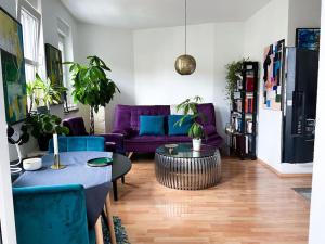 Beautiful bright apartment with balcony/10’ Mitte في برلين: غرفة معيشة مع أريكة أرجوانية وطاولة