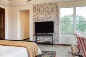 1 dormitorio con 1 cama y TV de pantalla plana en Hudson by AvantStay Magnificent Home w Beautiful Views Multiple Living Areas Pool Games en Austin