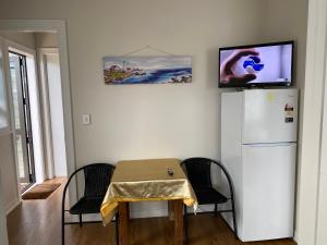 mesa y sillas con nevera y TV en Auckland GQ Flat bush holiday home, en Auckland