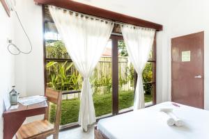 a bedroom with a large window with white curtains at Blauset Two in General Luna