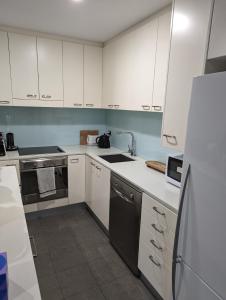 a kitchen with white cabinets and a sink and a refrigerator at The Heart of Glenelg in Glenelg