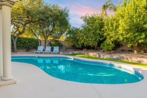 a swimming pool with two chairs and trees at Dwight by AvantStay Blissful Serene Oasis Pool Firepit Entertainers Patio in Phoenix