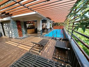 Skon Baga Bliss Hotel by Orion Hotels في Goa: منزل به مسبح وسطح خشبي