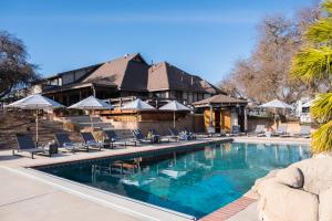 a swimming pool with chairs and umbrellas in front of a building at Cathedral by AvantStay Charming Secluded Estate w Sauna Pool Table Views of the Rolling Hills in Paso Robles