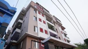 a tall white building with red windows at The Royals Home Stay in Deoghar
