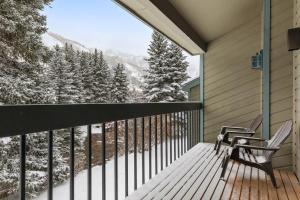 einen Balkon mit 2 Stühlen und Blick auf schneebedeckte Bäume in der Unterkunft Riverside Condos A102 by AvantStay Condo Close To Downtown Town Park Ski Lift 8 in Telluride