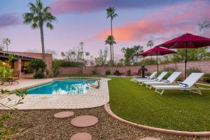 uma piscina com espreguiçadeiras e guarda-sóis num quintal em La Casona by AvantStay Gorgeous Spanish Style Oasis w Historic Charm Pool em Phoenix