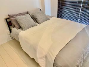 uma cama com lençóis brancos e almofadas num quarto em セカンド-privatespace Second- em Kurume