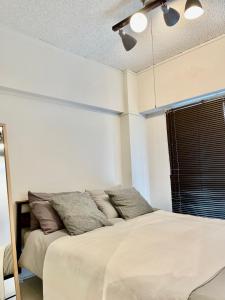 um quarto com uma cama com lençóis brancos e almofadas em セカンド-privatespace Second- em Kurume