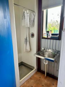 Baño pequeño con lavabo y espejo en Basic, Super 'Cosy' Cabin in The Middle of National Park and Mountains, en Otira