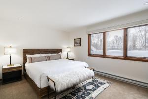 a white bedroom with a large bed and windows at Riverside Condos C202 by AvantStay Condo Close To Downtown Town Park Ski Lift 8 in Telluride