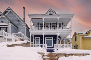 una casa bianca con un portico nella neve di Raddon by AvantStay Beautifully Restored Craftsman w Hot Tub in Heart of Downtown PC a Park City